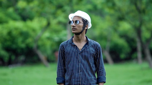 Portrait of cheerful young man wearing hardhat in farm side