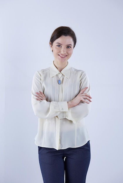 Portrait of cheerful young woman standing arms crossed over white background