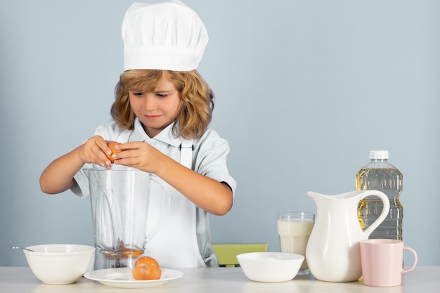 Portrait of chef child in cook hat cooking at home kid boy preparing food from vegetable and fruits