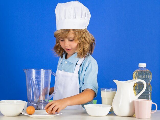 Portrait of chef child in cook hat cooking at home kid boy preparing food from vegetable and fruits