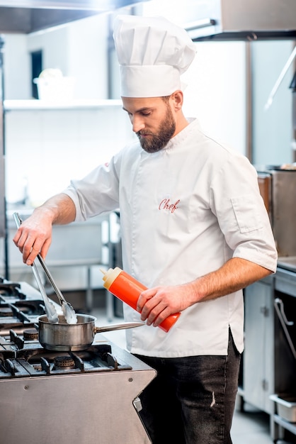 Portrait of chef cook in uniform with knifes at the restaurant kitchen