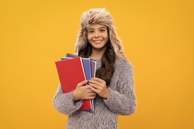 Portrait of child wearing warm clothes holding workbook express positive emotion