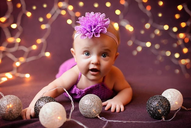 Portrait of a childgirl on a purple background with a garland that lies and smiles