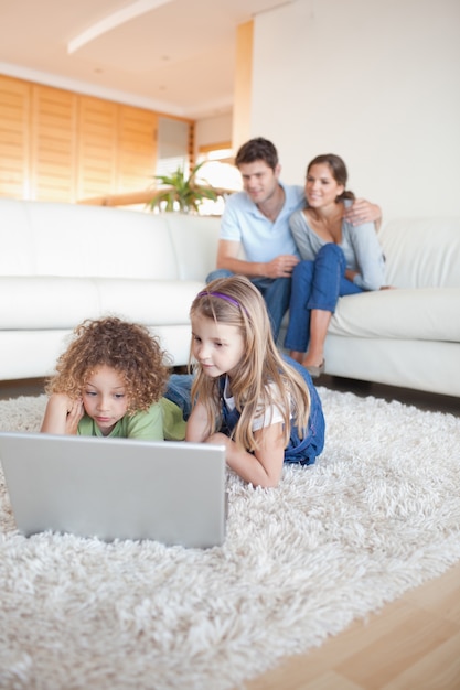 Portrait of children using a notebook while their parents are watching