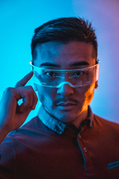 Portrait of chinese man with neon glasses with blue and orange light futuristic concept technology of cyber humans