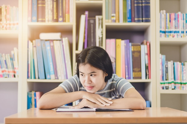 Portrait of clever Asian student reading and doing research in college library