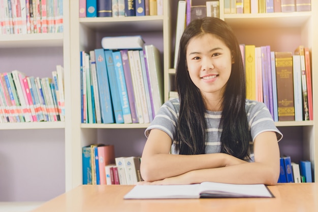 Portrait of clever Asian student reading and doing research in college library