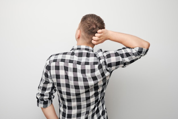 Portrait of clever man in shirt touching head thinks doubts chooses isolated on white studio background with copy space back view