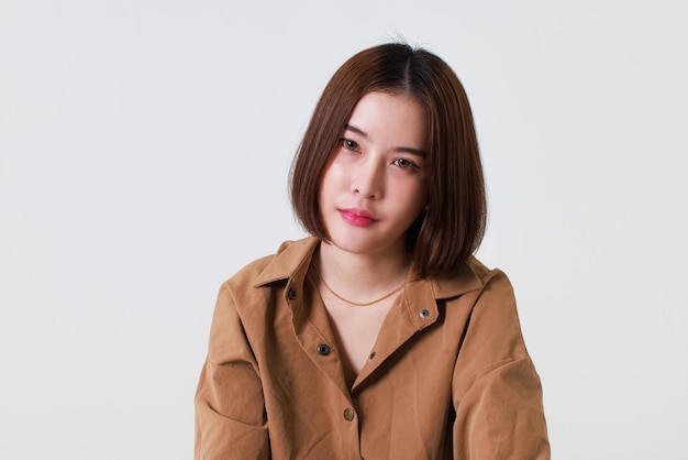 Portrait close up studio cutout shot of Asian stressed depressed worried thoughtful moody short hair female model in long sleeve brown shirt holding hand on forehead have headache on white background.