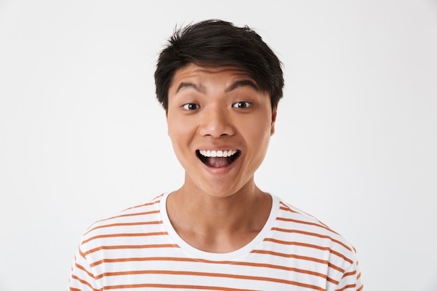 Portrait closeup of excited and happy chinese man wearing striped t-shirt smiling with perfect teeth and looking at you, isolated. Concept of emotions