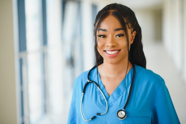 Portrait confident African American female doctor medical professional writing patient notes isolated on hospital clinic hallway windows background. Positive face expression