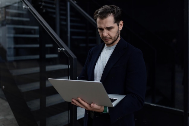 Portrait of a confident european businessman holding a laptop in his hands against the backdrop of