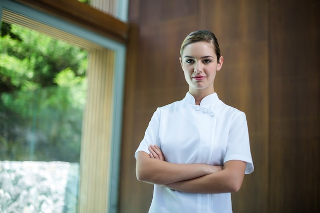 Portrait of confident female masseur standing with arms crossed