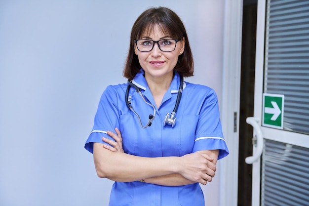 Portrait of confident female nurse with folded hands looking at camera