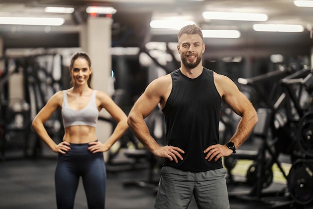 Photo portrait of a confident fit couple smiling at the camera in a gym