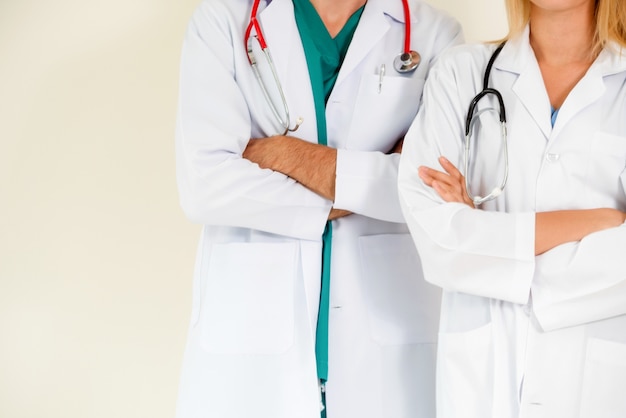 Portrait of confident GP doctor and surgical doctor with arms crossed on white background.