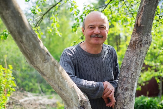 Portrait of confident male gardener standing near fruit tree