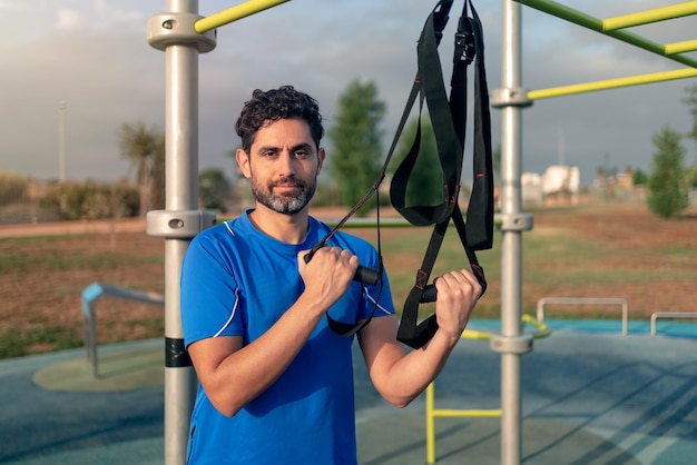 Portrait of confident man doing fitness exercises on a special hanging device