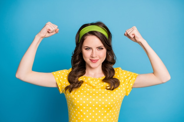 Portrait of confident proud girl show her strong biceps hands isolated over blue color background