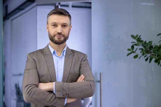 Portrait of a confident and serious male businessman standing in the office with his arms crossed on