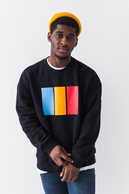 Portrait of confident sexy man in stylish sweatshirt on white wall