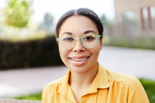 Portrait of confident smiling african american business woman wearing stylish eyeglasses looking at camera standing on the street Successful business