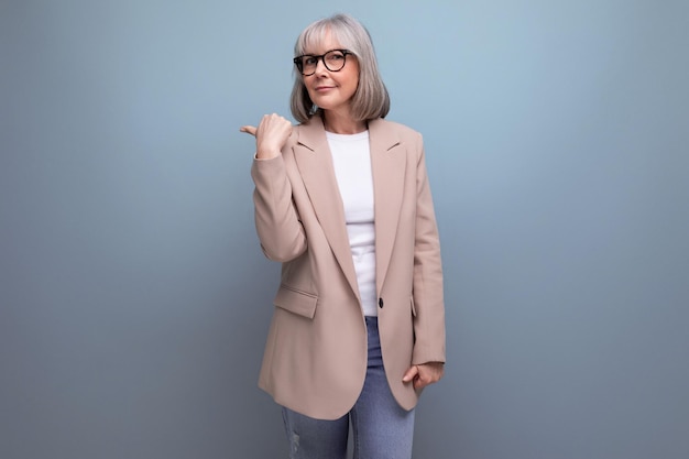 Portrait of confident stylish middle aged woman in business attire pointing aside on studio