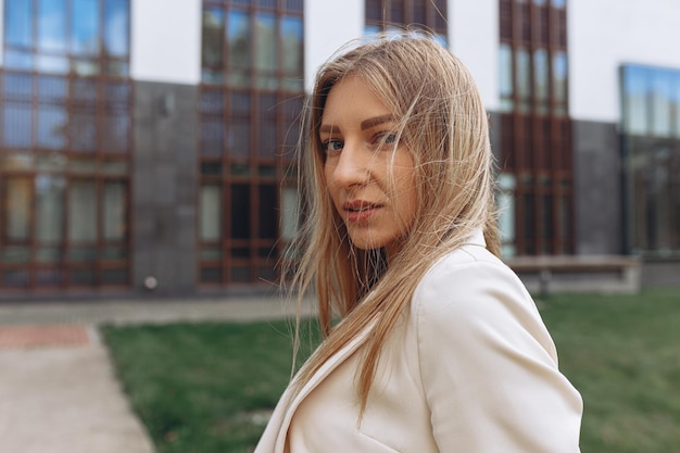 portrait of confident young businesswoman in white formal jacket with blond hair