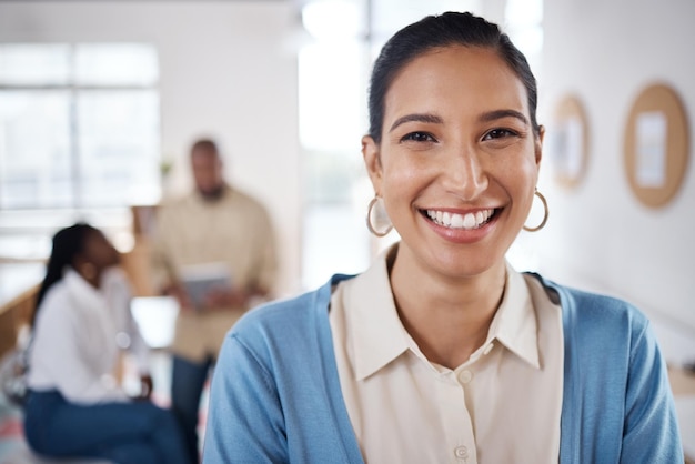 Portrait of a confident young businesswoman working in a modern office with her colleagues in the background