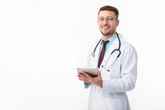 Portrait of confident young medical doctor on white background Holding a tablet in his hands