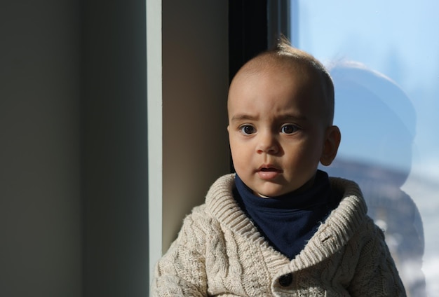 Portrait of a Confused face kid sitting beside the window