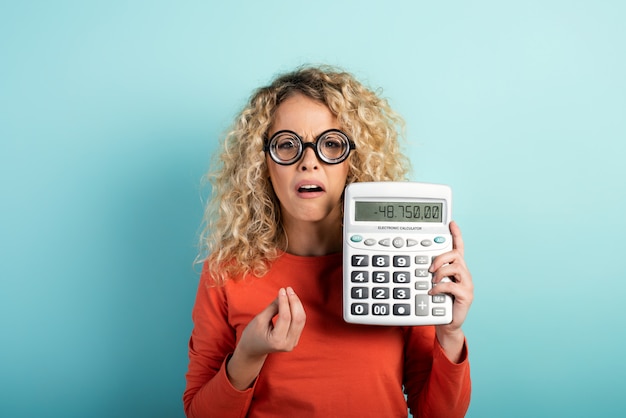 Portrait of a confused girl wearing glasses and holding a calculator