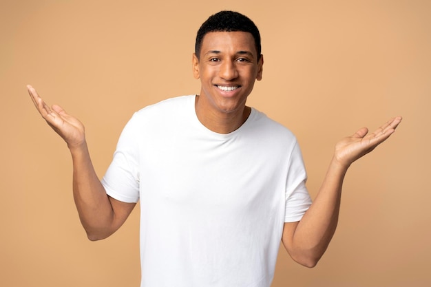 Portrait of confused handsome young man standing with raised arms and looking at camera