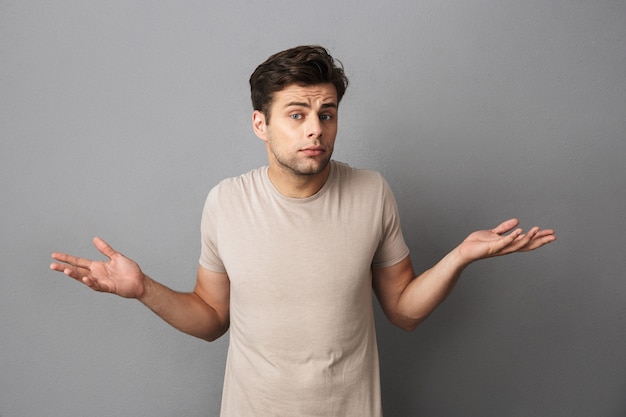 Portrait of a confused young man in t-shirt isolated