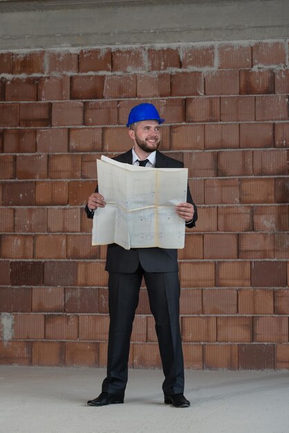 Portrait Of Construction Master With Blue Helmet And Blueprint In Hands