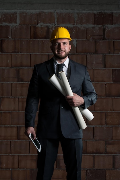 Portrait Of Construction Master With Yellow Helmet And Blueprint In Hands