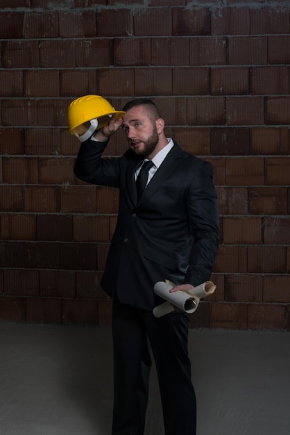 Portrait Of Construction Master With Yellow Helmet And Blueprint In Hands