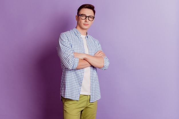 Portrait of cool charismatic guy folded arms look camera wear glasses on purple background