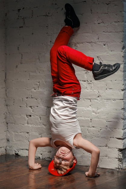 Portrait of cool young hip hop boy in red hat and red pants and white shirt in the loft