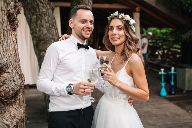 Photo portrait of couple with arm around holding wineglasses while standing outdoors