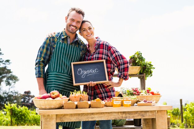 Portrait of couple with blackboard selling organic vegetables