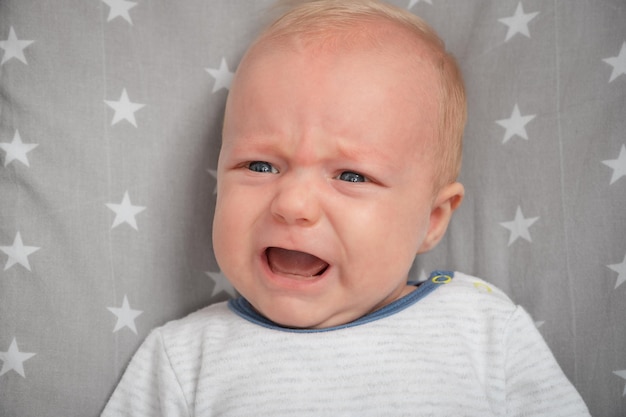 Portrait of crying newborn baby closeup Cut child with blue eyes Face expression