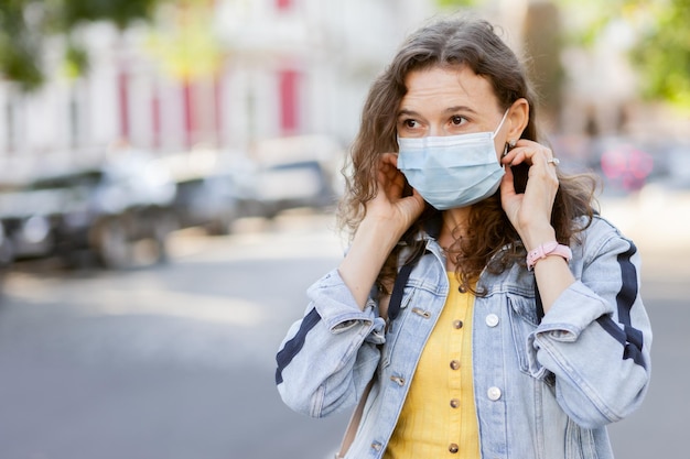 Portrait of curly haired woman in medical mask in city