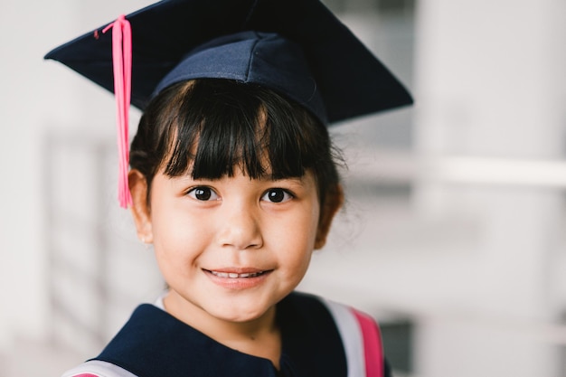 Portrait of a cute Asian graduated schoolgirl with graduation gown in school