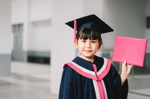 Portrait of a cute Asian graduated schoolgirl with graduation gown in school