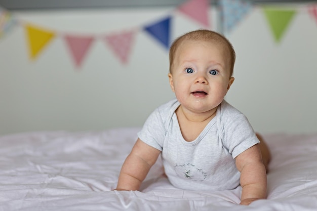 Portrait of cute baby girl on bed at home