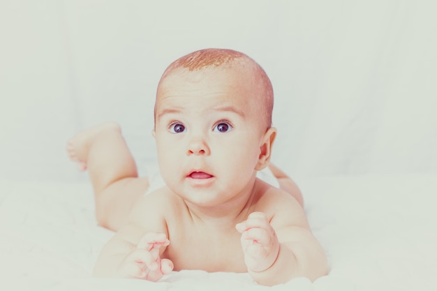 Portrait of a cute baby lying on the white textile