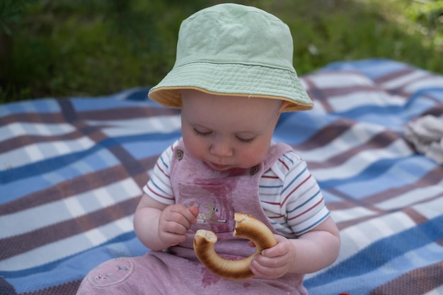 Portrait of cute baby with bread in her hands eating during picnic