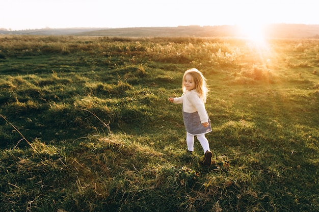 Portrait of a cute beatiful and happy girl running through the sunny field 