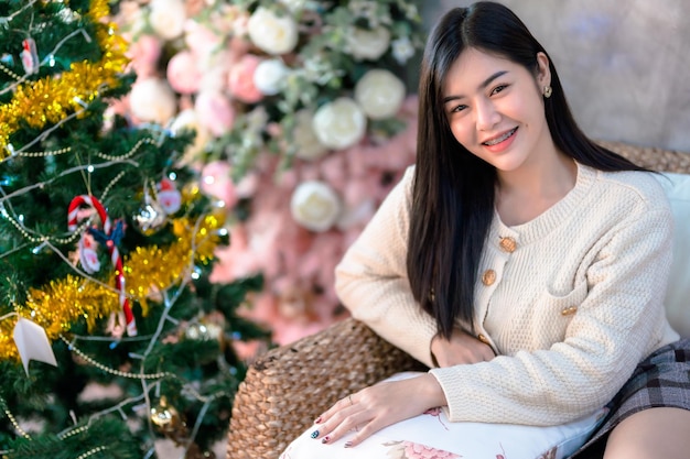 Portrait Cute beautiful positive smile young asian woman decorating to a Christmas tree at home in the living room indoors Decoration During Christmas xmas and New Year holidays